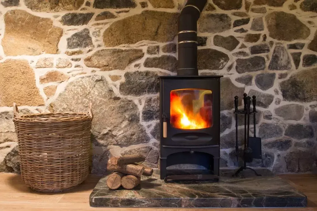 Poêle à bois installé devant un mur en pierres apparentes